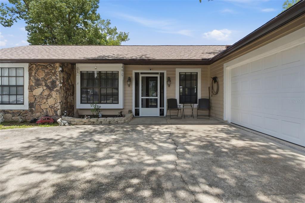 The exterior of a single-story house features a stone facade, beige siding, and a garage — 5906 W WOODHILL COURT, CRYSTAL RIVER, FL
