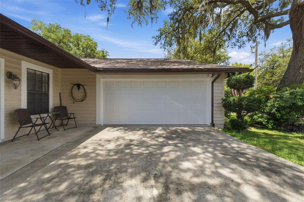 A concrete driveway leads to a single-car garage attached to a tan-sided house — 5906 W WOODHILL COURT, CRYSTAL RIVER, FL