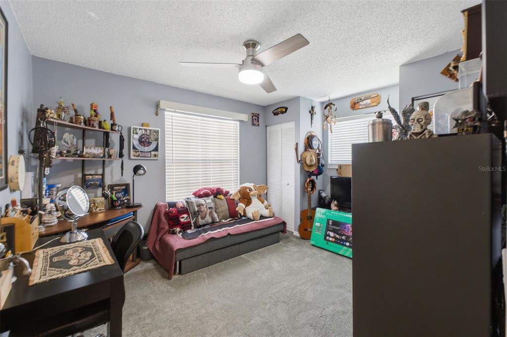 A bedroom with gray walls, a ceiling fan, a sofa bed, and a desk area — 5906 W WOODHILL COURT, CRYSTAL RIVER, FL