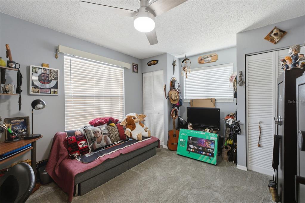 A bedroom features a gray sofa, a television on a box, and a ceiling fan — 5906 W WOODHILL COURT, CRYSTAL RIVER, FL