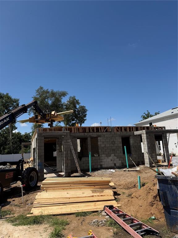 A construction site shows a concrete block structure with a forklift lifting wooden beams — 613 SILVER STREAM COURT, BRANDON, FL