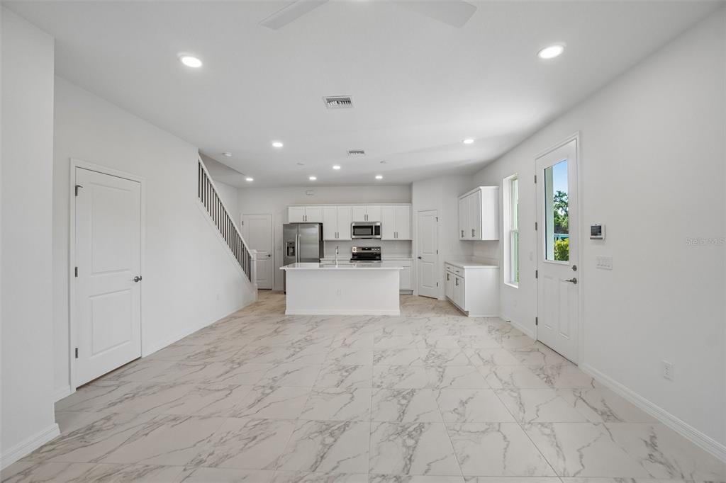 A modern kitchen with white cabinets, a central island, and marble-patterned tile flooring — 613 SILVER STREAM COURT, BRANDON, FL