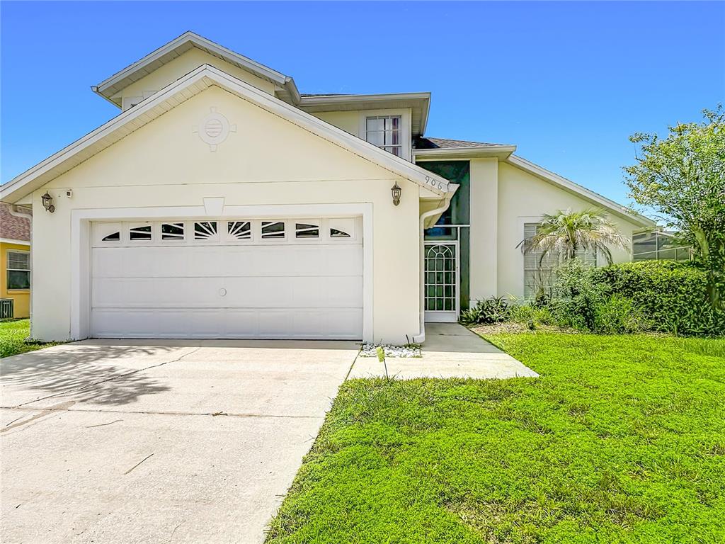 A two-story house with a white stucco exterior, a two-car garage, and a front lawn — 906 MONTANA AVENUE, DAVENPORT, FL