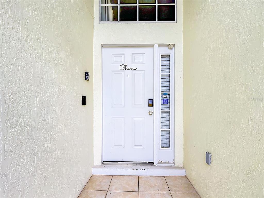 A white front door with the word Ohana written on it sits under a transom window — 906 MONTANA AVENUE, DAVENPORT, FL