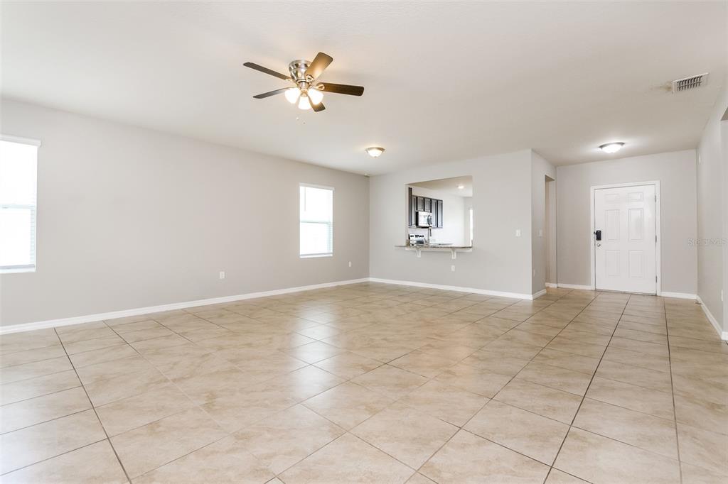 An open-concept living area features light-colored walls, large floor tiles, and a ceiling fan — 571 AUTUMN STREAM DRIVE, AUBURNDALE, FL