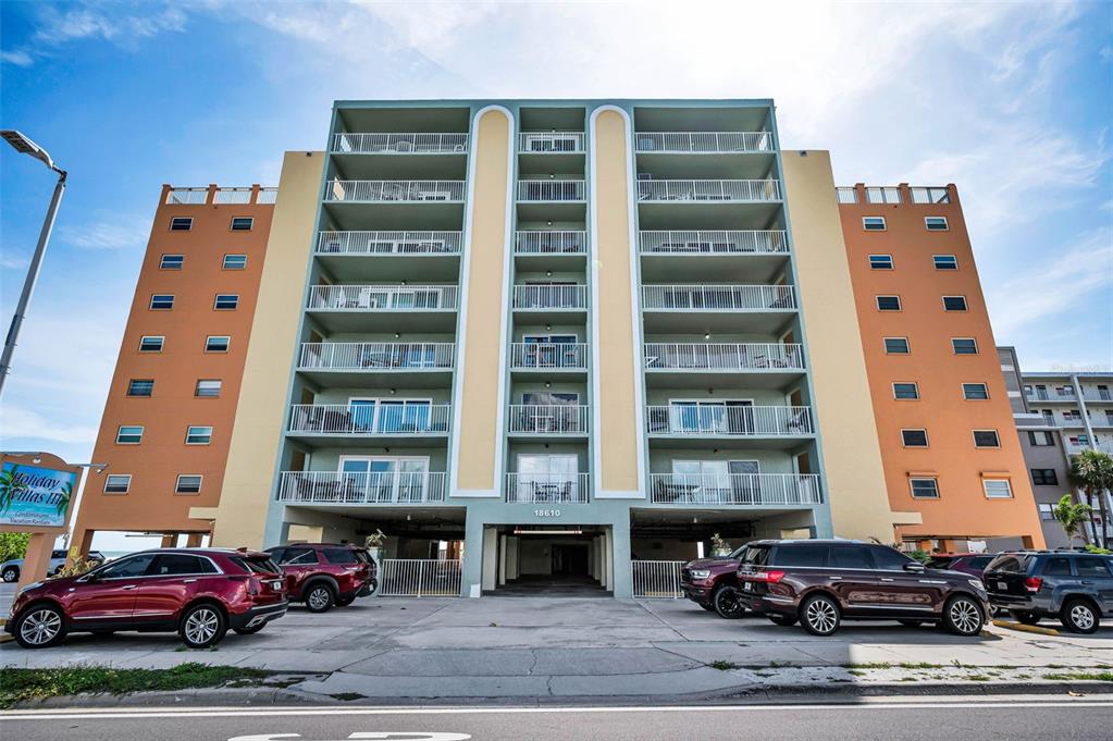 A multi-story apartment building with balconies and a ground-level parking area — 18610 GULF BOULEVARD UNIT 610, INDIAN SHORES, FL