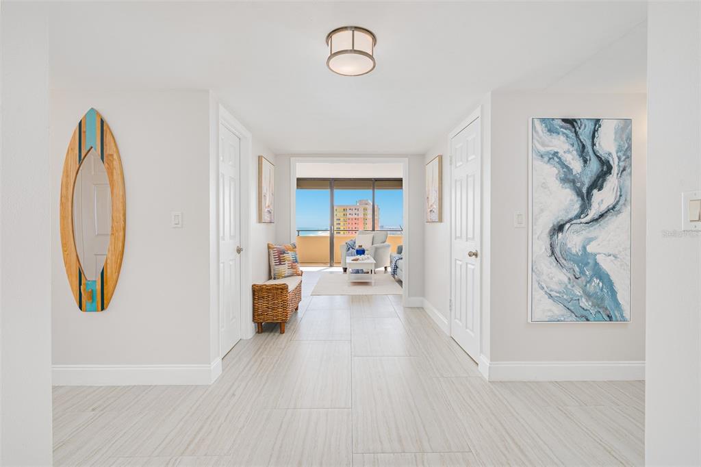 A bright hallway with light tile flooring leads to a living area with ocean views — 2200 N ATLANTIC AVENUE UNIT 1502, DAYTONA BEACH, FL
