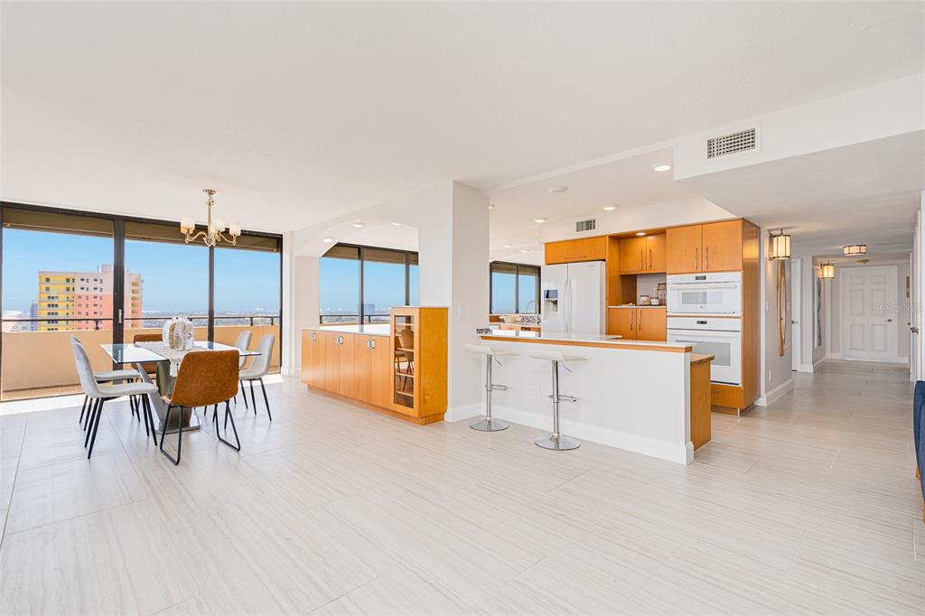 A bright, open-concept dining and kitchen area with light tile flooring and floor-to-ceiling windows — 2200 N ATLANTIC AVENUE UNIT 1502, DAYTONA BEACH, FL