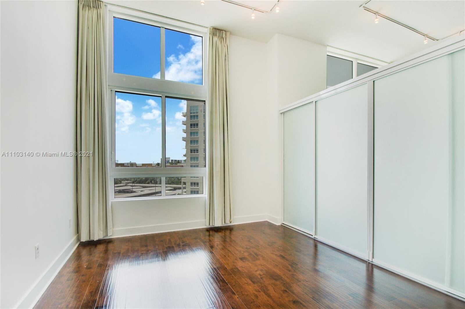 A room with hardwood floors, floor-to-ceiling windows, and large sliding glass closet doors — 1900 N Bayshore Drive # 912, Miami FL 33132, MIAMI, FL