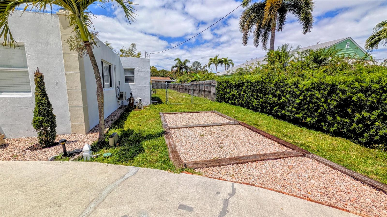 A gravel patio area with wooden borders sits in a grassy backyard beside a house — 407 NW 7th Street # A, Boynton Beach FL 33426, BOYNTON BEACH, FL