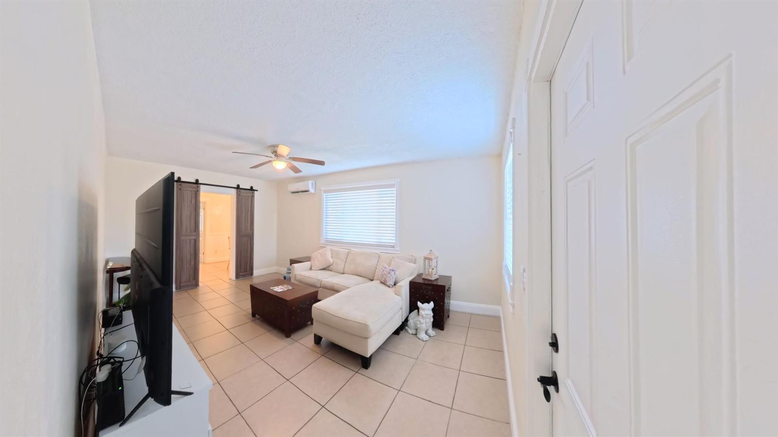 A living room features a sectional sofa, a coffee table, and a television on tile flooring — 407 NW 7th Street # A, Boynton Beach FL 33426, BOYNTON BEACH, FL