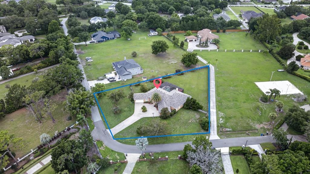 An aerial view shows a house with a pool enclosure on a large grassy lot — 9427 EDDINGS ROAD, ODESSA, FL