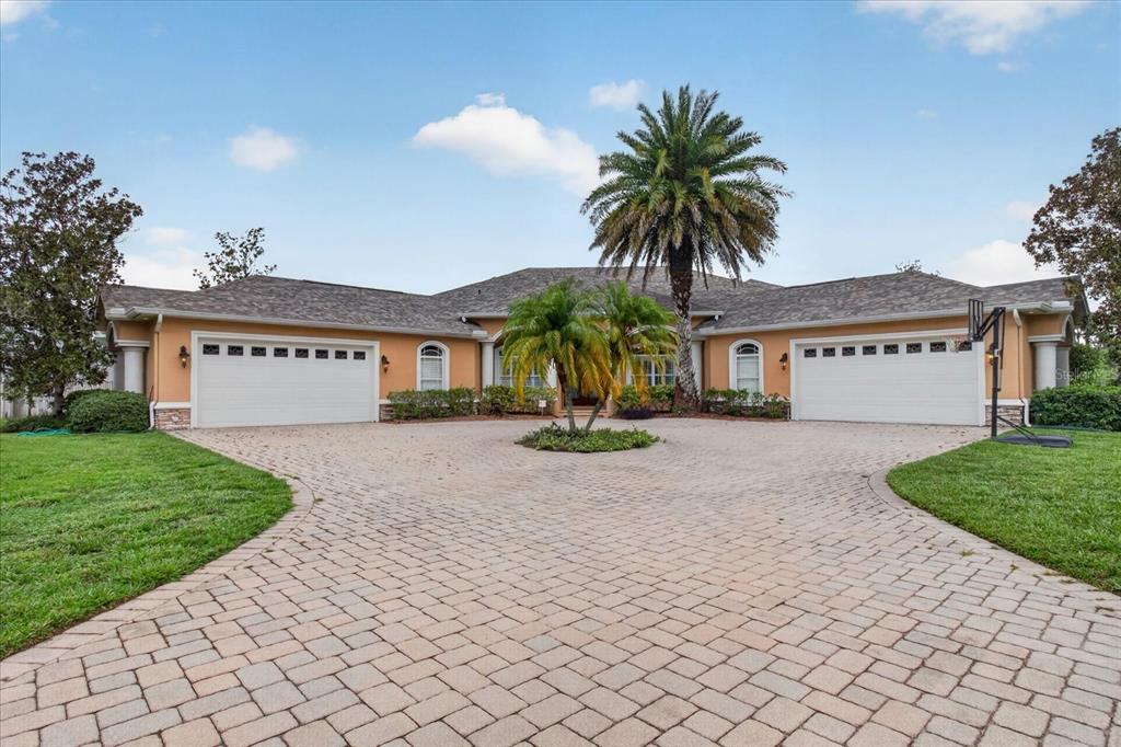 A single-story house with two garages and a paved circular driveway featuring palm trees — 9427 EDDINGS ROAD, ODESSA, FL