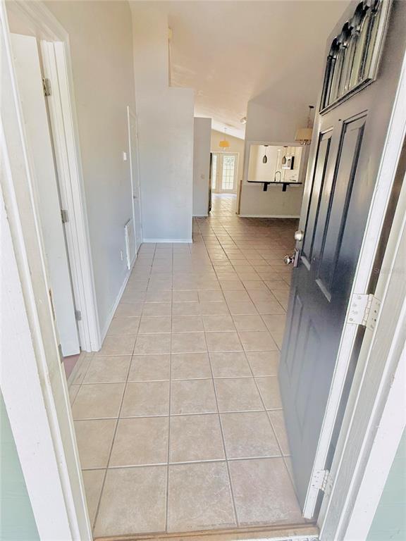 An open entryway with light-colored tile flooring leads into a living area with a kitchen — 2232 NE 13TH AVENUE, GAINESVILLE, FL