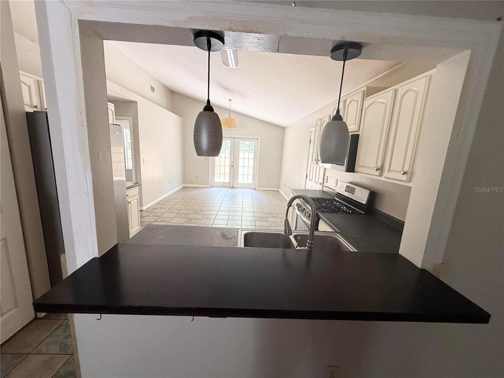 A kitchen pass-through window overlooks a tiled dining area with glass doors — 2232 NE 13TH AVENUE, GAINESVILLE, FL
