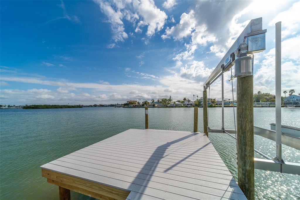A wooden dock with a boat lift extends over a calm bay under a blue sky — 1217 BAY SHORE BOULEVARD, INDIAN ROCKS BEACH, FL