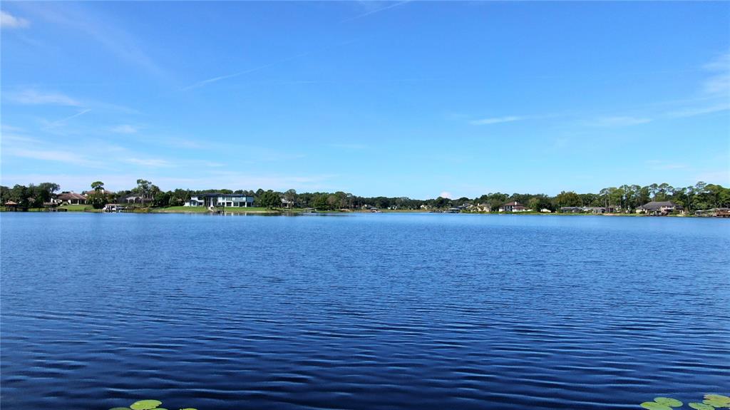 A wide view of a lake surrounded by houses and trees under a blue sky — LAKE MARKHAM ROAD, SANFORD, FL