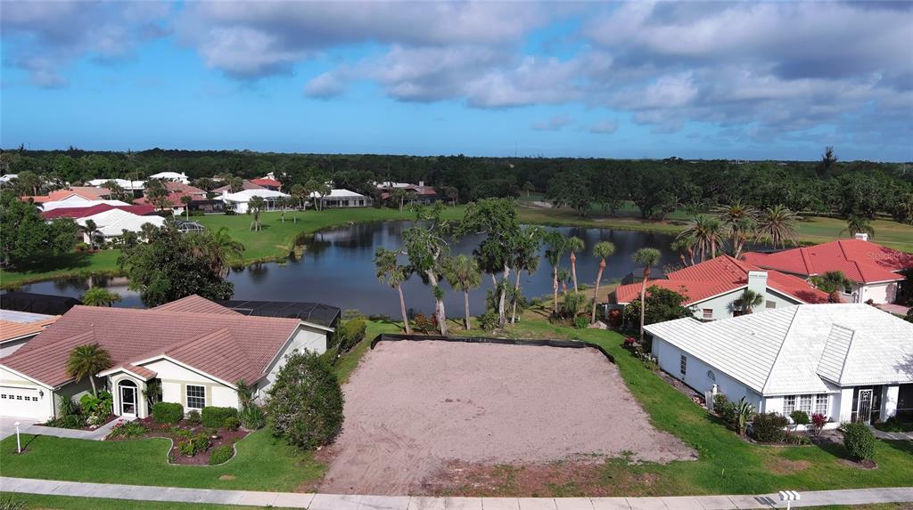 An aerial view shows a vacant residential lot situated between two houses near a lake — 1717 KILRUSS DRIVE, VENICE, FL