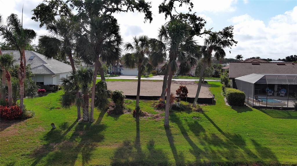 An aerial view shows a cleared, sandy residential lot situated between two houses with palm trees — 1717 KILRUSS DRIVE, VENICE, FL