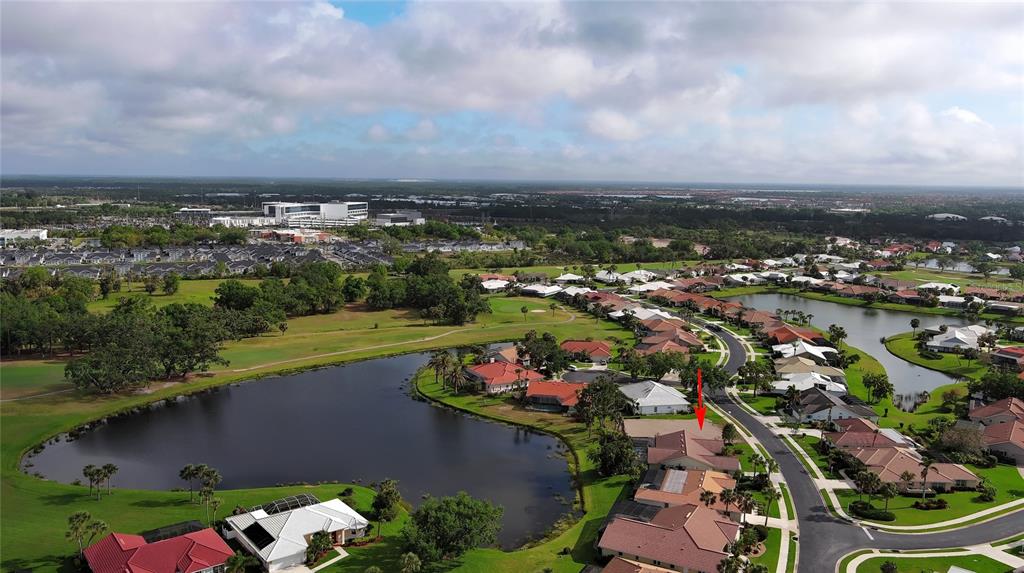 An aerial view shows a residential neighborhood with houses surrounding a lake and golf course — 1717 KILRUSS DRIVE, VENICE, FL