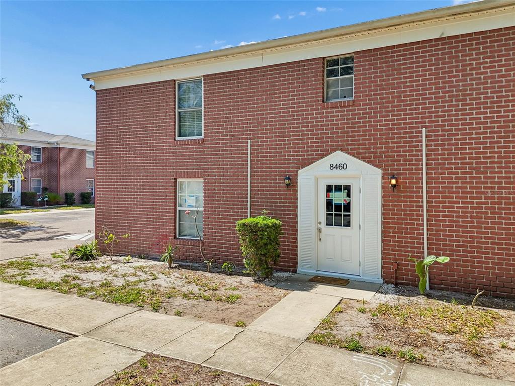 A two-story red brick apartment building with a white front door and sidewalk — 8460 13TH STREET N UNIT B, ST PETERSBURG, FL