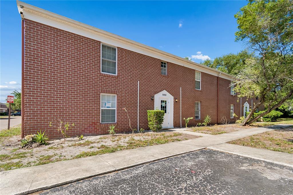 A two-story red brick apartment building features a white front door and concrete walkway — 8460 13TH STREET N UNIT B, ST PETERSBURG, FL