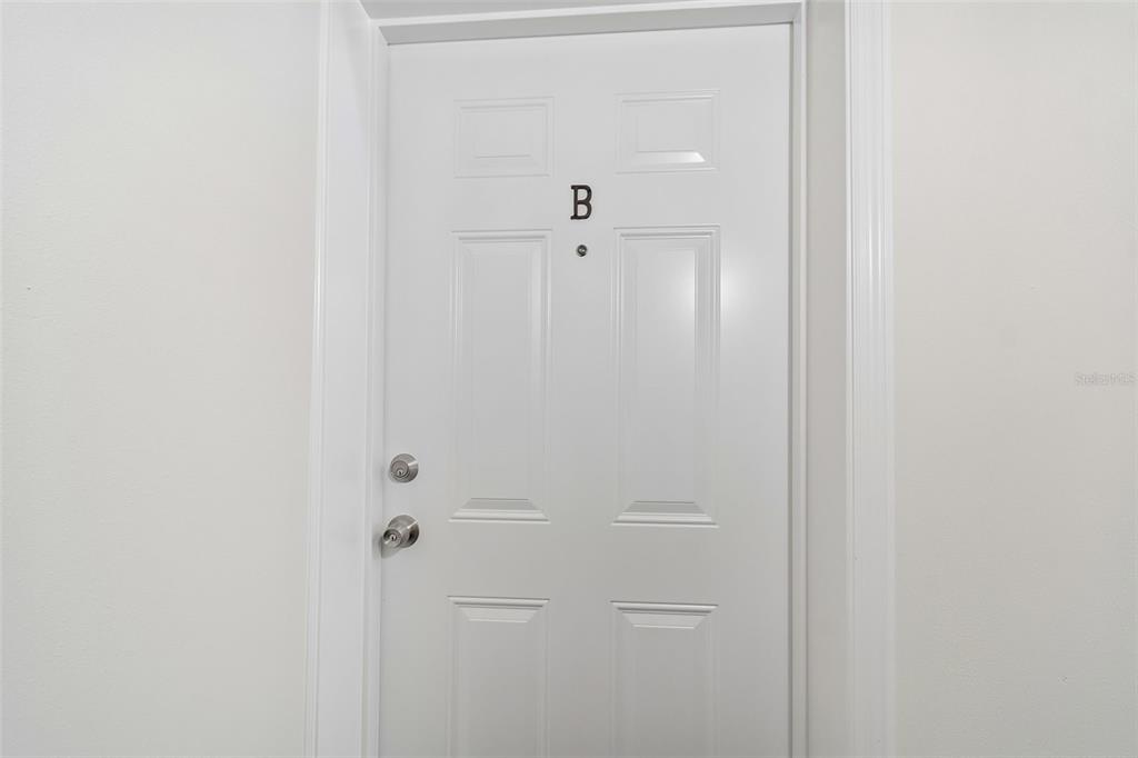 A white interior door labeled with the letter B features a peephole and hardware — 8460 13TH STREET N UNIT B, ST PETERSBURG, FL
