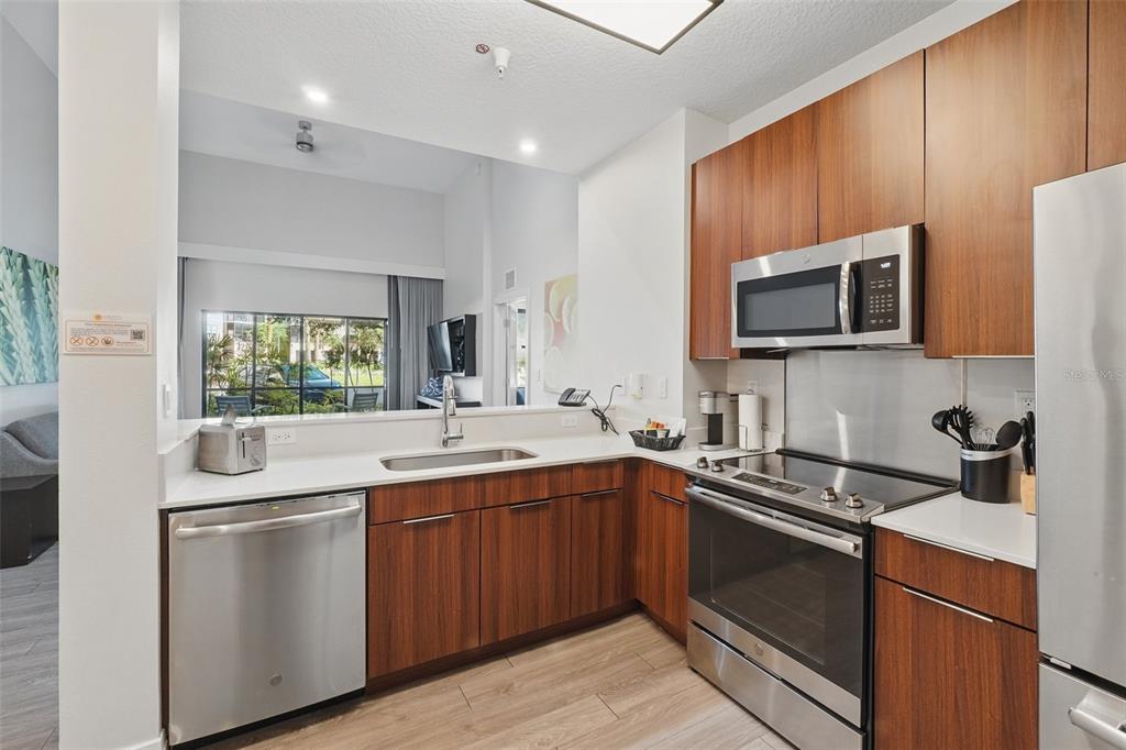 A modern kitchen features wood cabinets, stainless steel appliances, and a white countertop — 14501 GROVE RESORT AVENUE UNIT 2103, WINTER GARDEN, FL