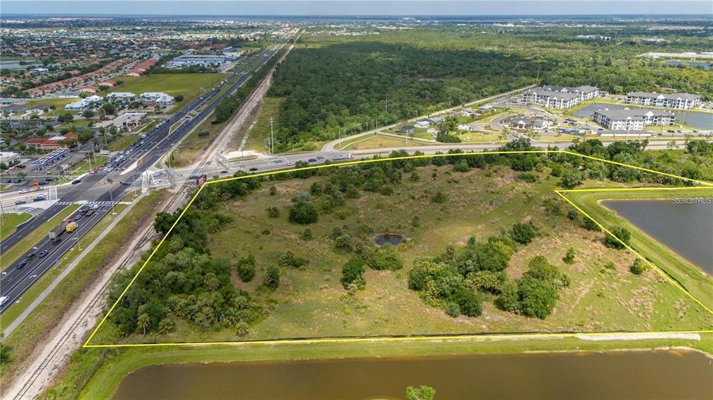 An aerial view shows a vacant, grassy lot outlined in yellow near a highway — 10000 TAMIAMI TRAIL, PUNTA GORDA, FL