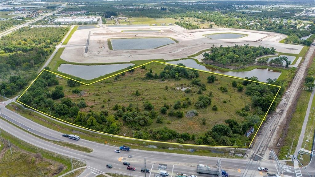 An aerial view shows a vacant, irregularly shaped plot of land bordered by a road — 10000 TAMIAMI TRAIL, PUNTA GORDA, FL