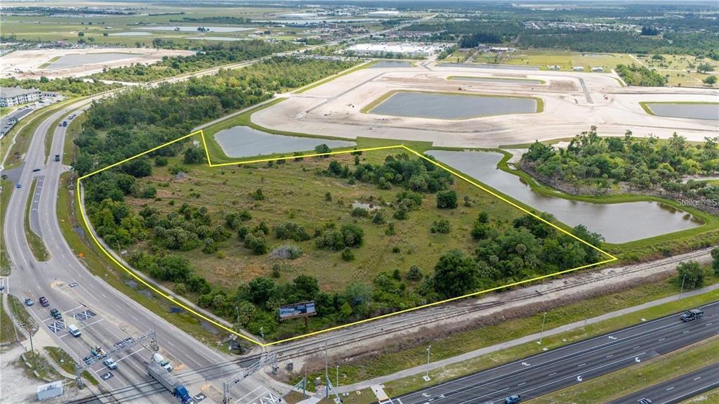 An aerial view shows a vacant, partially wooded lot outlined in yellow near a highway — 10000 TAMIAMI TRAIL, PUNTA GORDA, FL