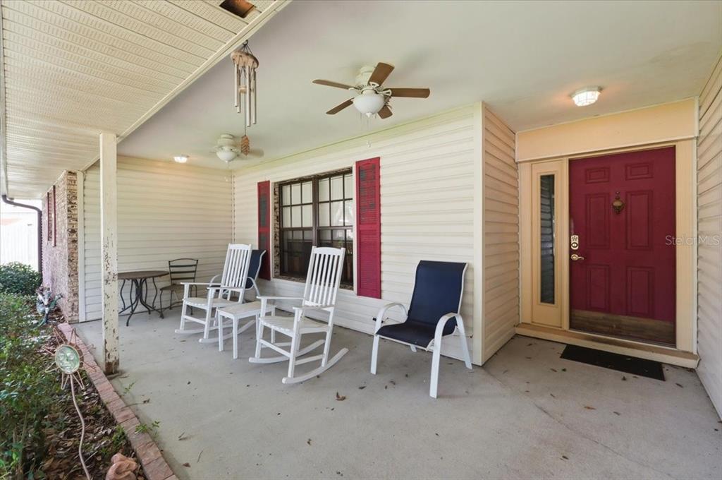 A covered front porch features a red door, white rocking chairs, and ceiling fans — 1700 VARNER COURT, BARTOW, FL
