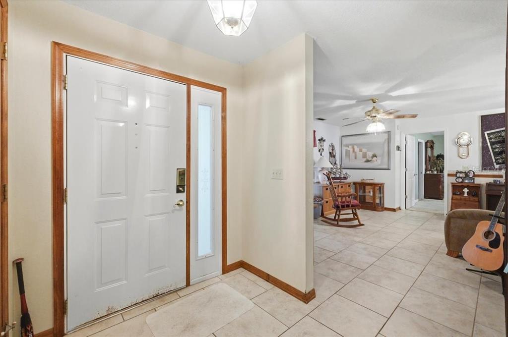 An entryway with a white front door, tiled floors, and a view into a living area — 1700 VARNER COURT, BARTOW, FL