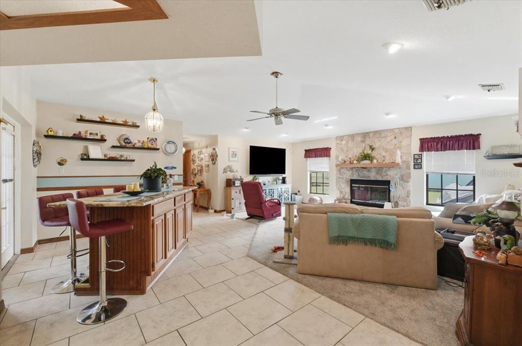 An open-concept living room and kitchen area with tile flooring, a fireplace, and bar seating — 1700 VARNER COURT, BARTOW, FL
