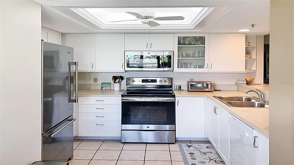 A kitchen with white cabinets, stainless steel appliances, and tile flooring under a tray ceiling — 1327 SIESTA BAYSIDE DRIVE UNIT 1327-C, SARASOTA, FL