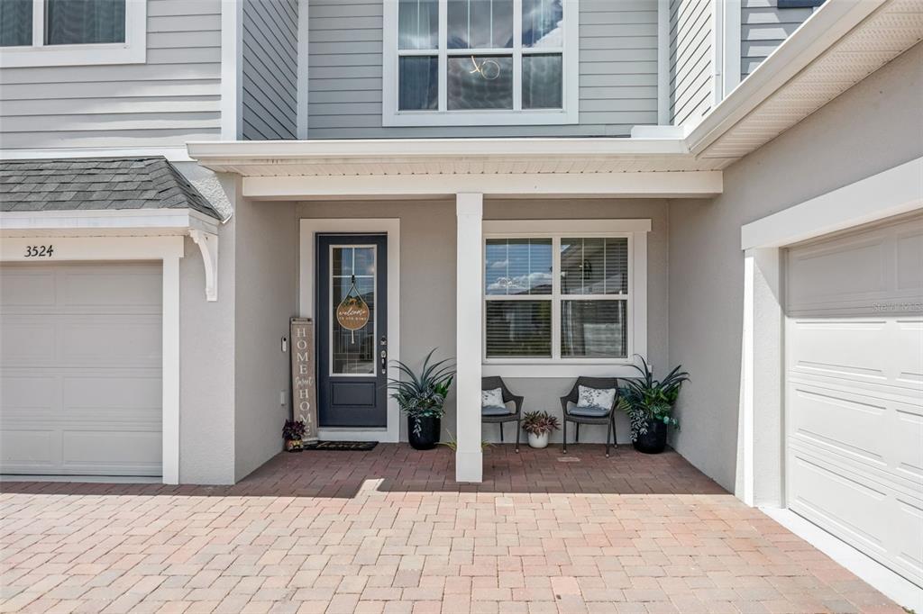 A gray two-story house exterior features a brick-paved entryway, a front door, and two garages — 3524 BANANA SHRUB BOULEVARD, CLERMONT, FL