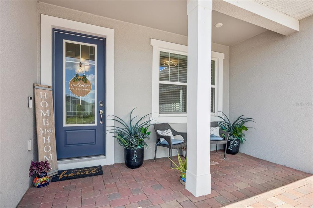 A covered front porch features a blue door, two chairs, and potted plants — 3524 BANANA SHRUB BOULEVARD, CLERMONT, FL