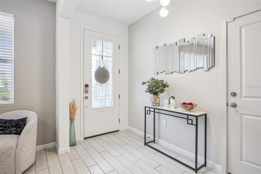 A bright entryway features a white front door, a console table, and a wall mirror — 3524 BANANA SHRUB BOULEVARD, CLERMONT, FL