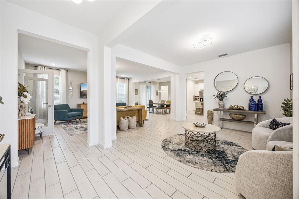 An open-concept living area features light tile flooring, neutral walls, and multiple seating arrangements — 3524 BANANA SHRUB BOULEVARD, CLERMONT, FL