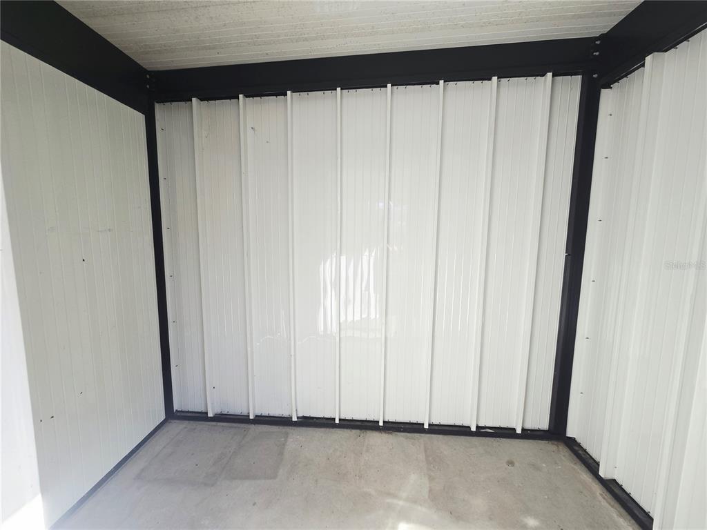 The exterior of a home features a light green stucco wall, a dark door, and gravel — 6425 DREXEL DRIVE UNIT 2, PORT RICHEY, FL