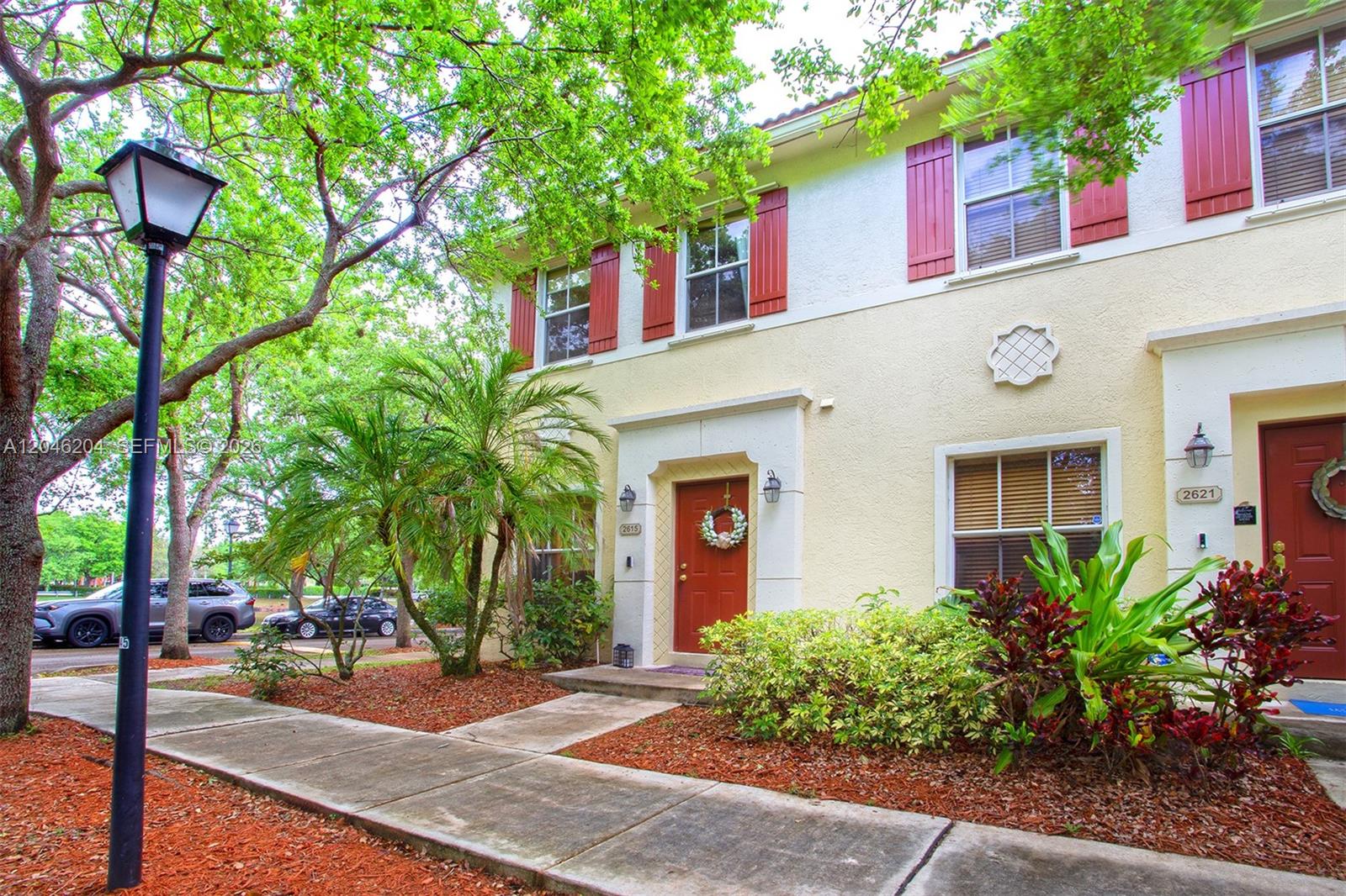Two-story townhouses with yellow stucco walls, red shutters, and front doors with wreaths — 2615 SW 100th Ave # 2615, Miramar FL 33025, MIRAMAR, FL