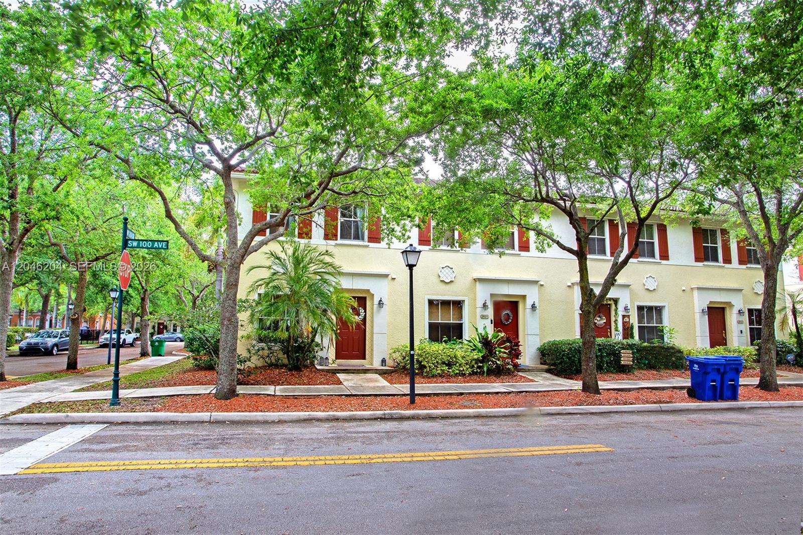 A row of two-story townhouses with yellow stucco walls and red doors under large trees — 2615 SW 100th Ave # 2615, Miramar FL 33025, MIRAMAR, FL