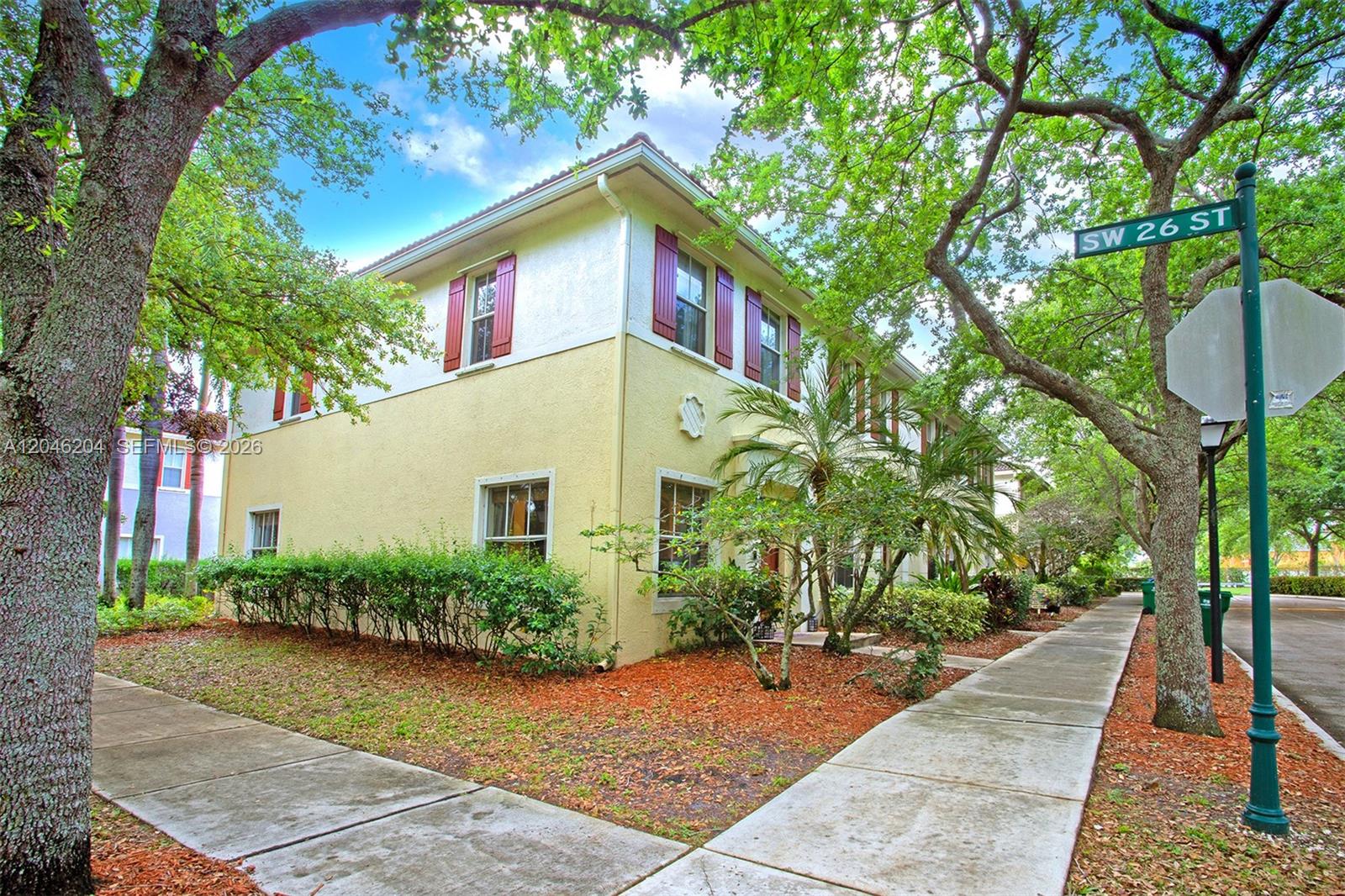 A two-story yellow stucco building with red shutters stands beside a sidewalk and trees — 2615 SW 100th Ave # 2615, Miramar FL 33025, MIRAMAR, FL
