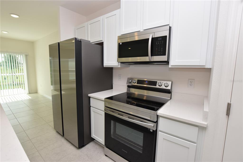 A kitchen features white cabinets, stainless steel appliances, and light-colored countertops — 3905 ACADEMIA AVENUE, LAKELAND, FL