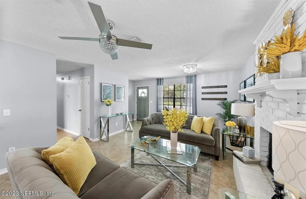 A living room features two gray sofas, a glass coffee table, and a white fireplace — 1121 LONDONDERRY DRIVE, ORANGE PARK, FL
