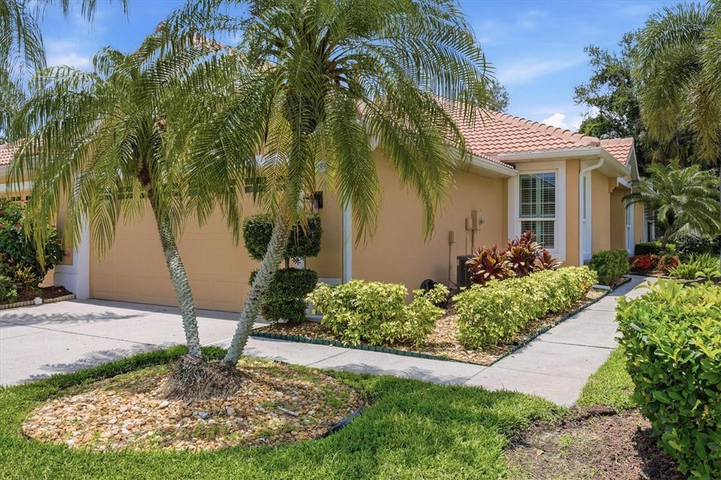 A tan house with a tile roof, a palm tree, and a concrete walkway — 4939 WHISPERING OAKS DRIVE, NORTH PORT, FL