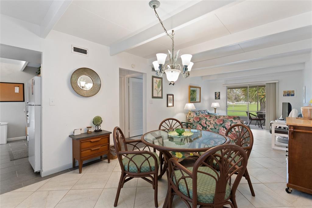 A dining area with a glass table and wicker chairs sits before an open living room — 1823 CLUB CIRCLE, LAKE WALES, FL