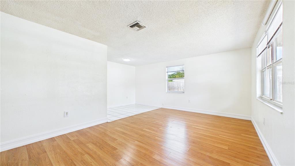 A room with wood-look flooring, white walls, a tiled area, and a window — 6132 100TH CIRCLE, PINELLAS PARK, FL