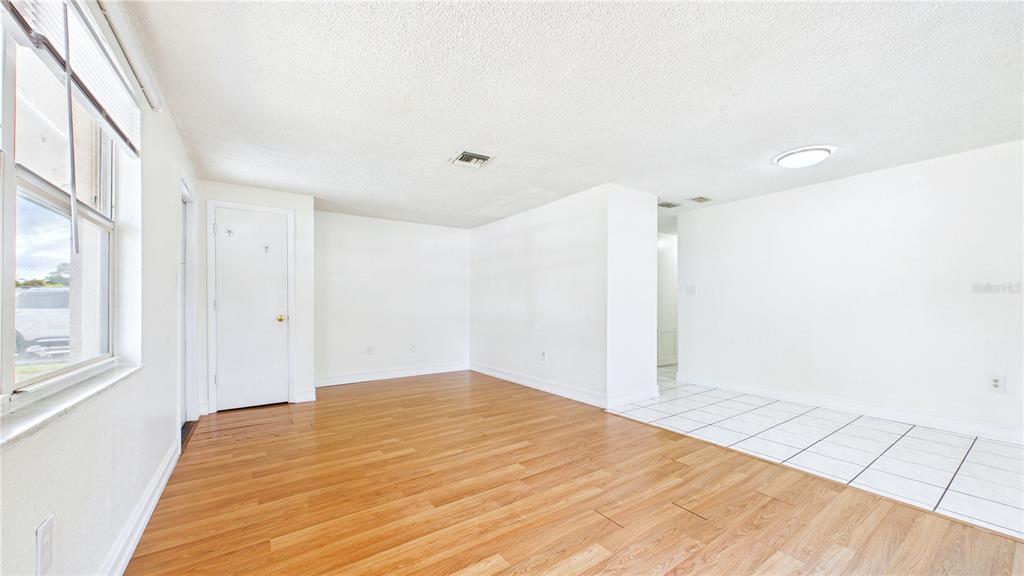 An interior view of a room with wood-look flooring, white walls, and a tiled area — 6132 100TH CIRCLE, PINELLAS PARK, FL