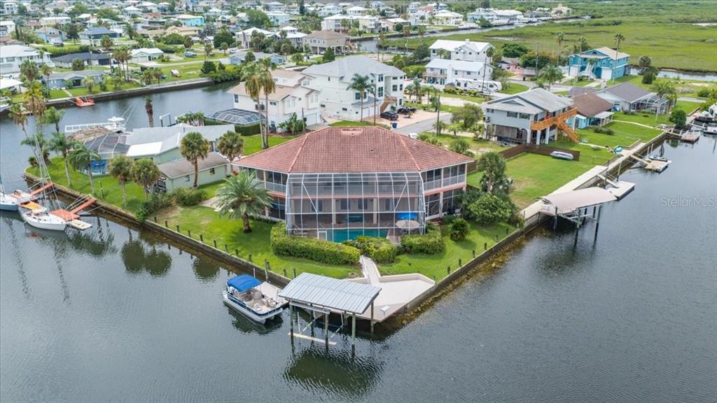 An aerial view shows a waterfront house with a pool, screened lanai, and private dock — 4295 NEWPORT DRIVE, HERNANDO BEACH, FL